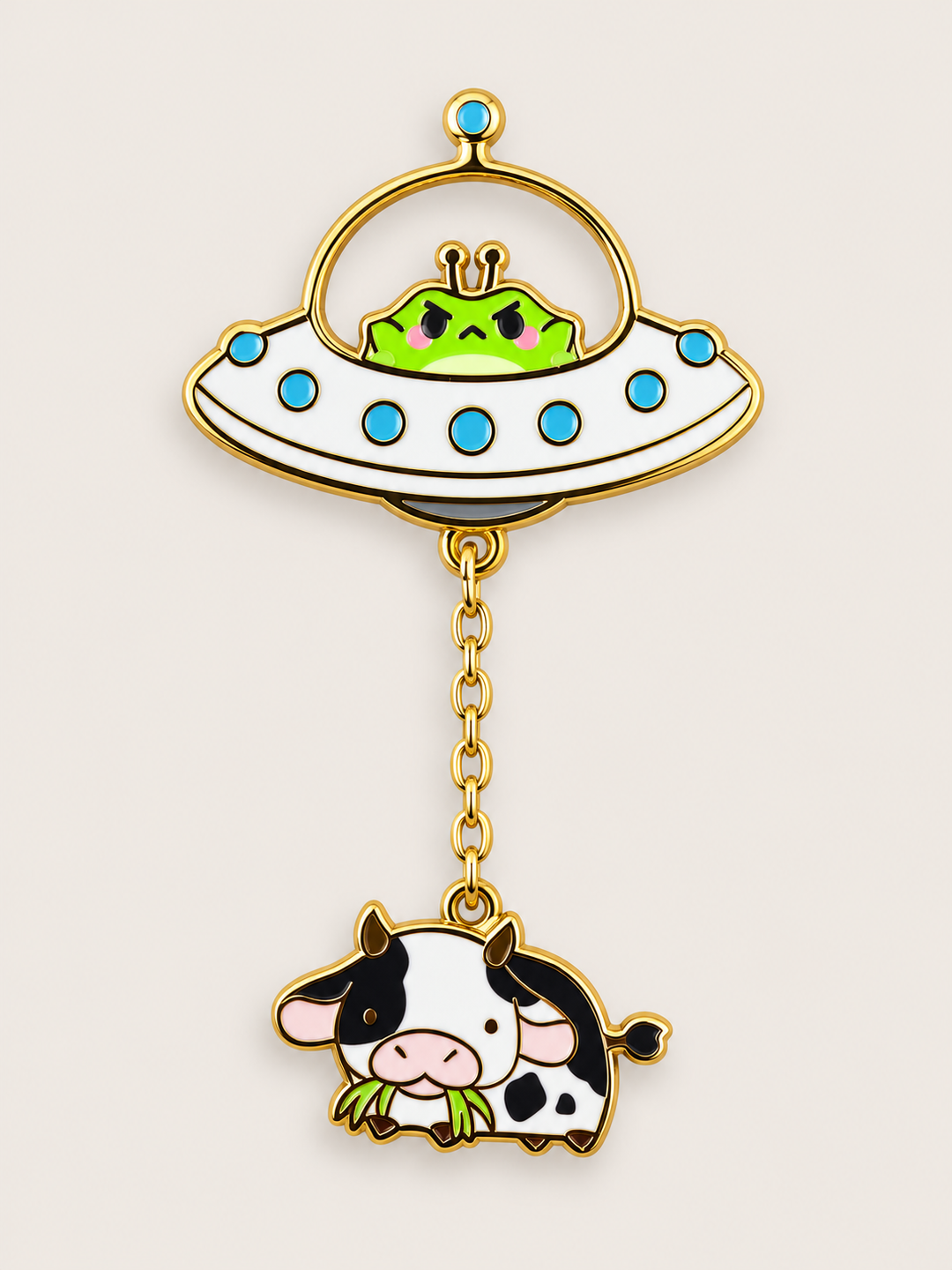 Alien Cow UFO Dangle Pin shown on a warm neutral background