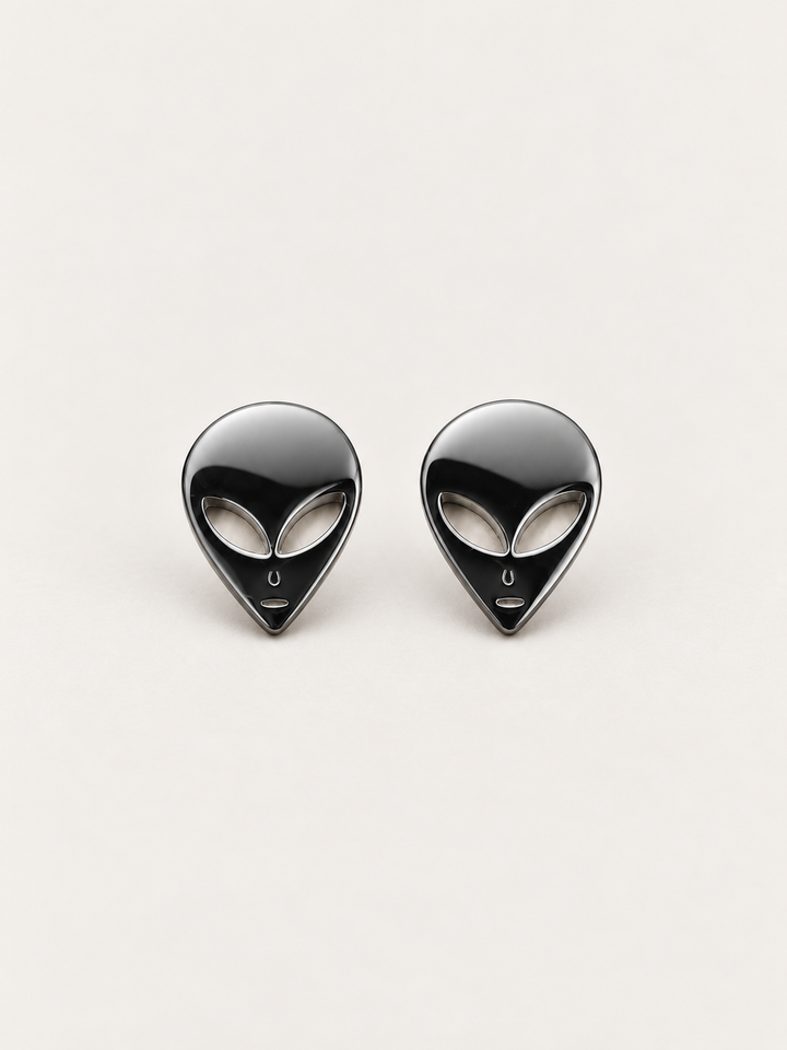 Black Alien Head Stud Earrings shown angled on a warm neutral background