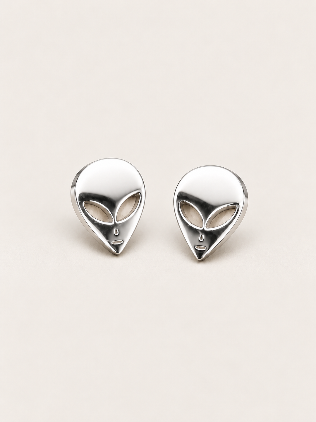 Silver Alien Head Stud Earrings shown angled on a warm neutral background