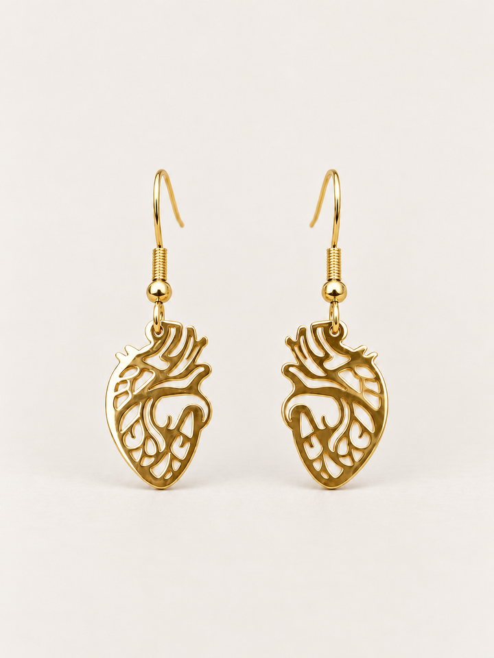 Anatomical Heart Drop Earrings in gold shown on a warm neutral background