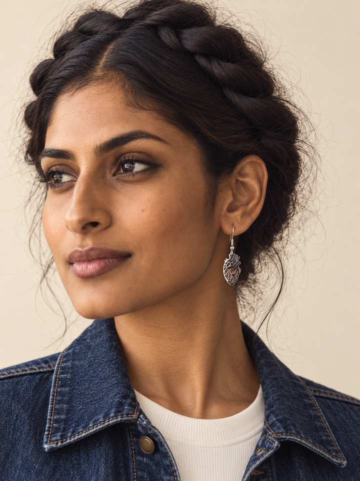 Anatomical Heart Drop Earrings in silver worn by a model with skin visible through the openwork heart