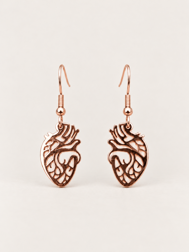 Anatomical Heart Drop Earrings in rose gold shown on a warm neutral background