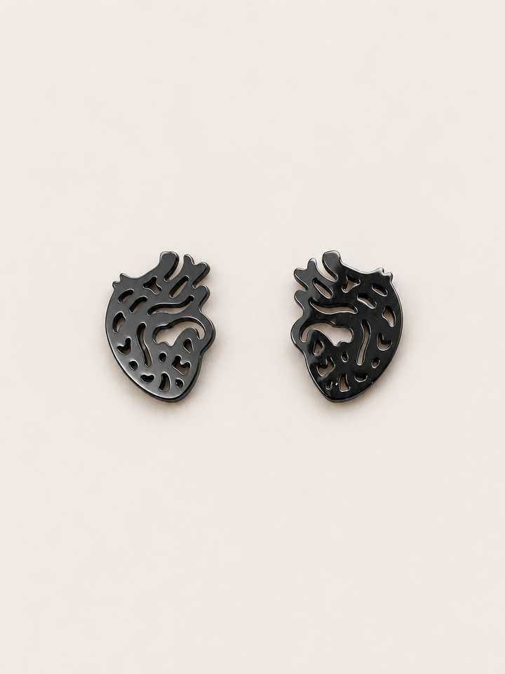 Anatomical Heart Stud Earrings in black shown on a warm neutral background