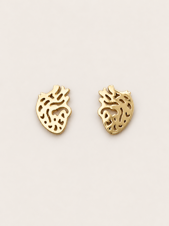 Anatomical Heart Stud Earrings in gold shown on a warm neutral background