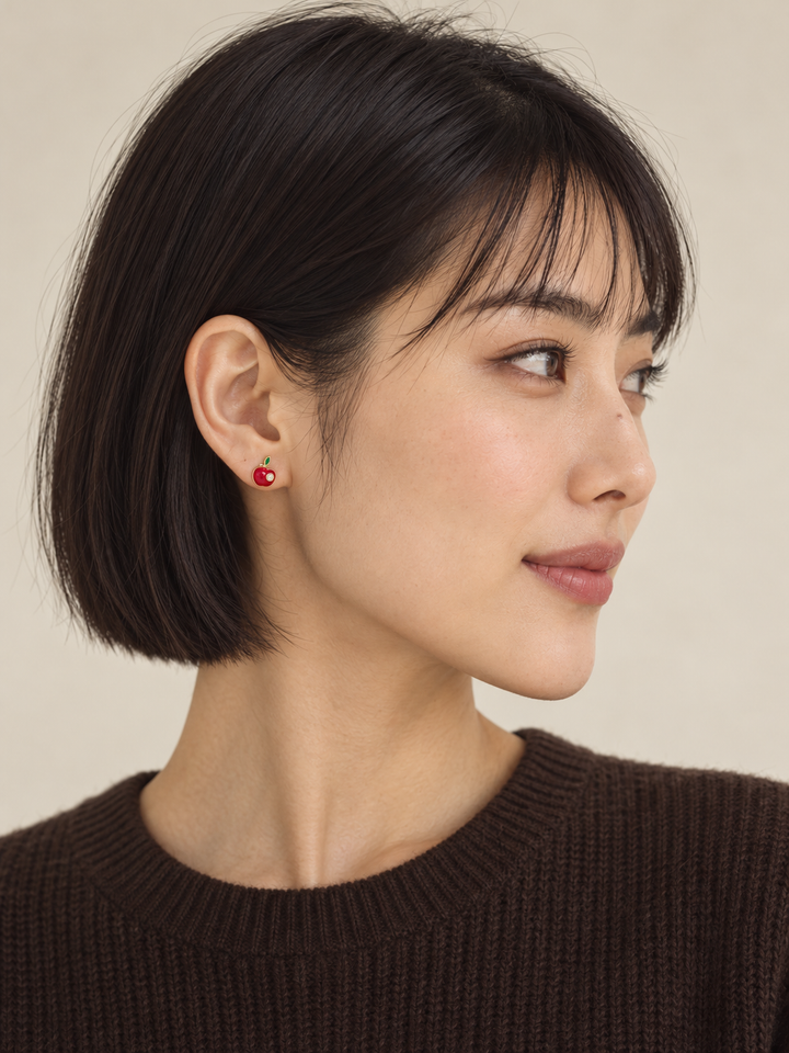 Red apple stud worn on the viewer-left ear