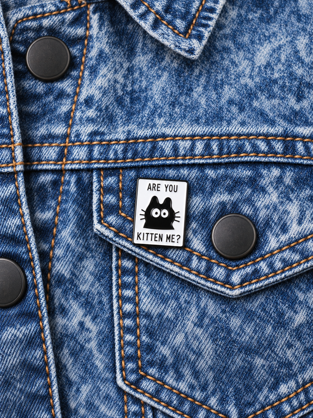 Are You Kitten Me Pin displayed on a blue denim jacket beside a metal button