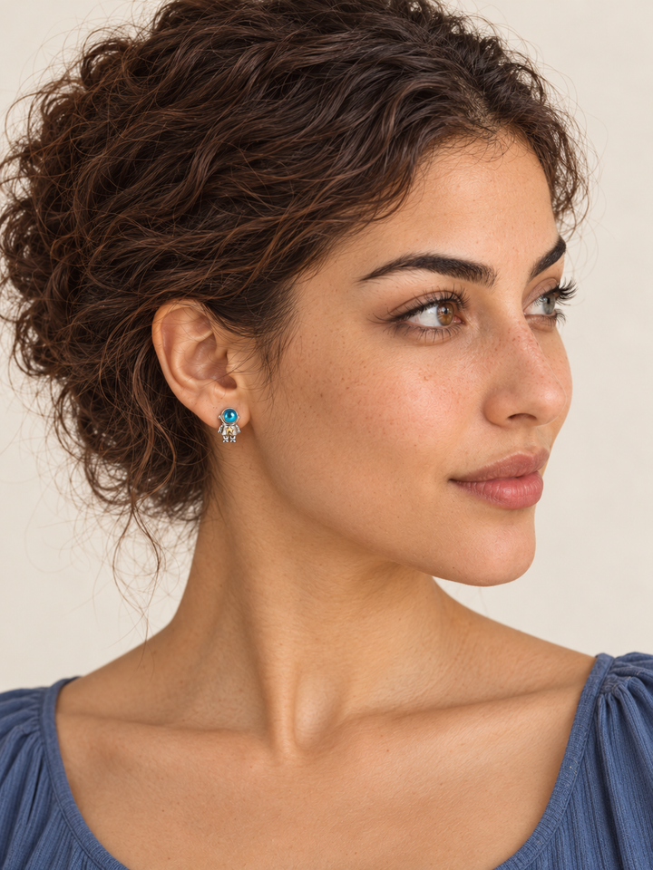 Astronaut Earrings on the viewer-left ear, showing the astronaut with both arms down