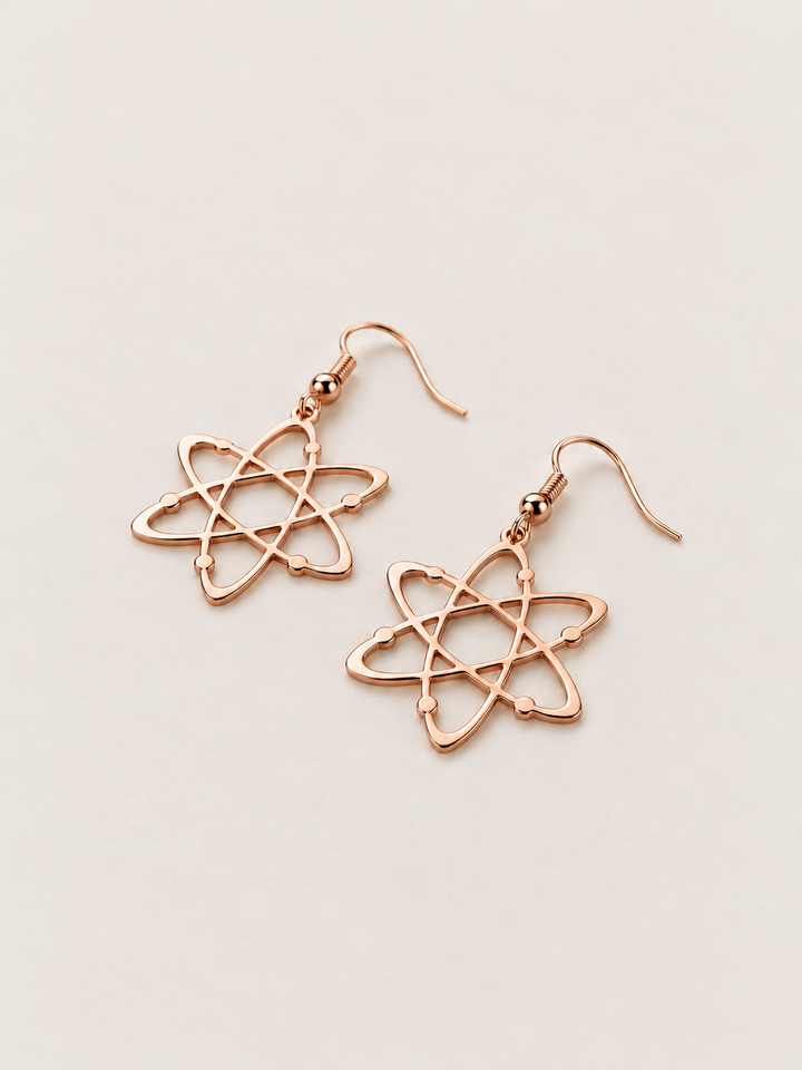 Rose Gold Atom Drop Earrings lying flat at an angle on a warm neutral background