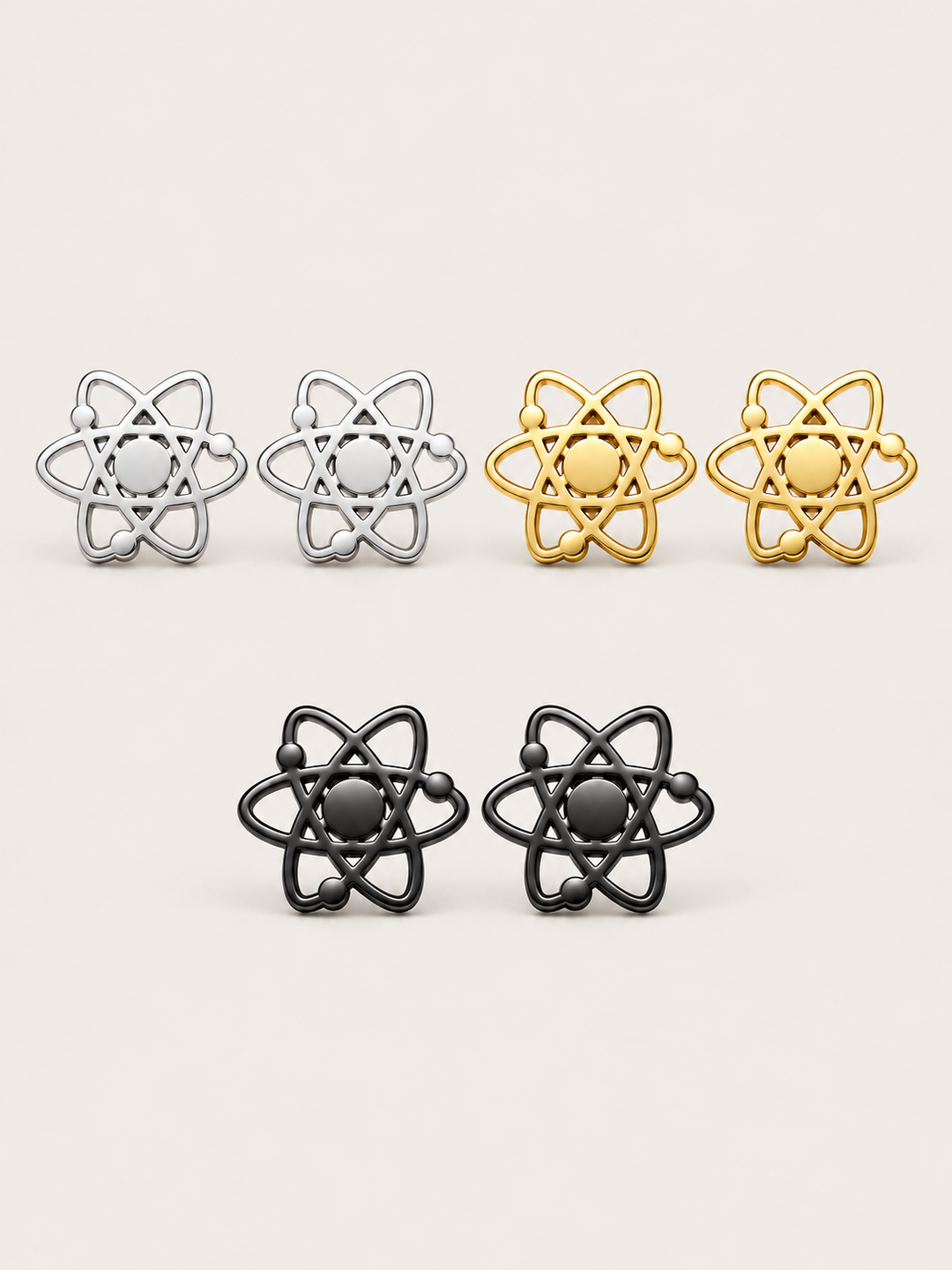 Atom Stud Earrings in Silver, Gold and Black stainless steel on a warm neutral background