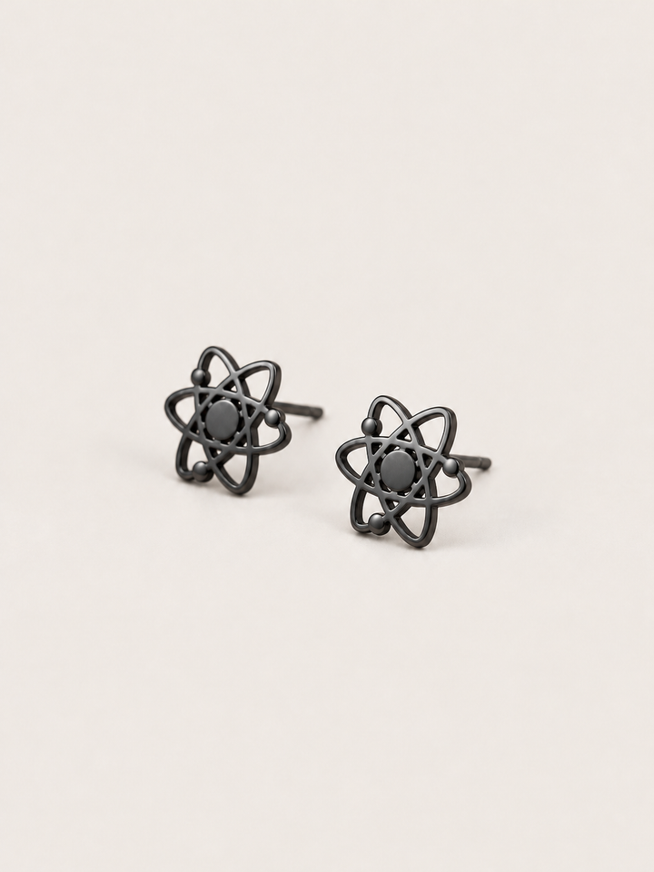 Atom Stud Earrings in black shown at an angle on a warm neutral background