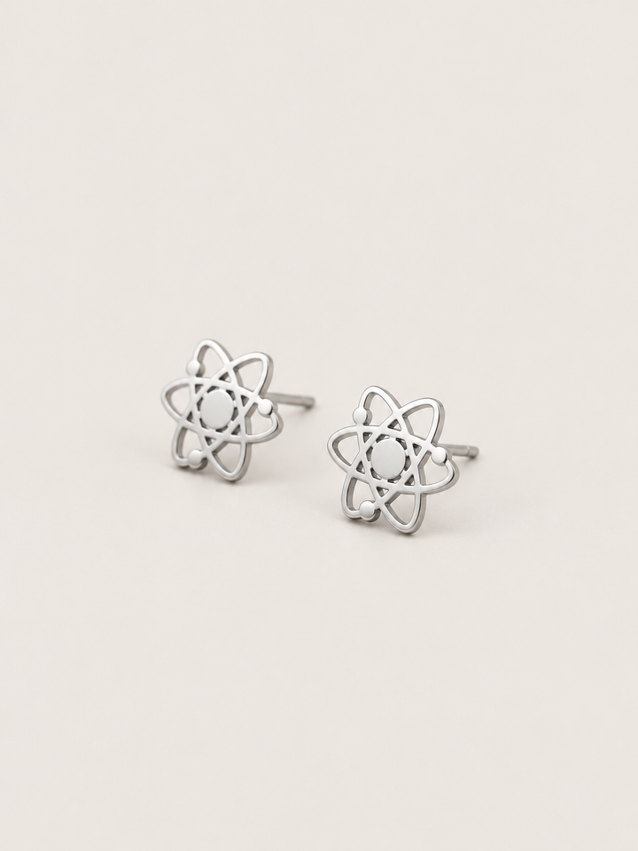 Atom Stud Earrings in silver shown at an angle on a warm neutral background