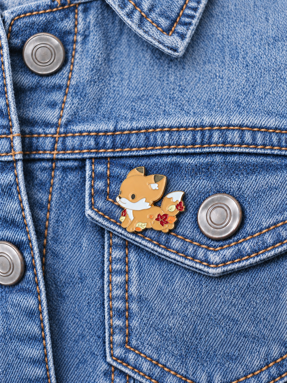 Autumn Fox with Leaves Pin displayed on a light-wash denim jacket beside a metal button