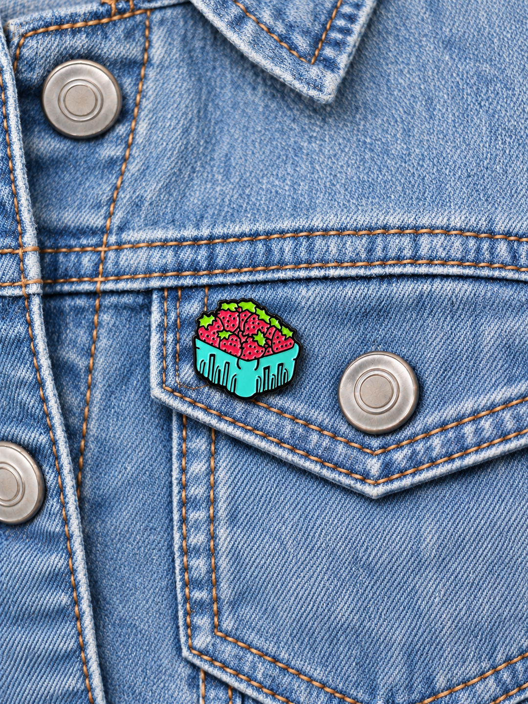 Basket of Strawberries Pin displayed on a light-wash denim jacket beside a metal button