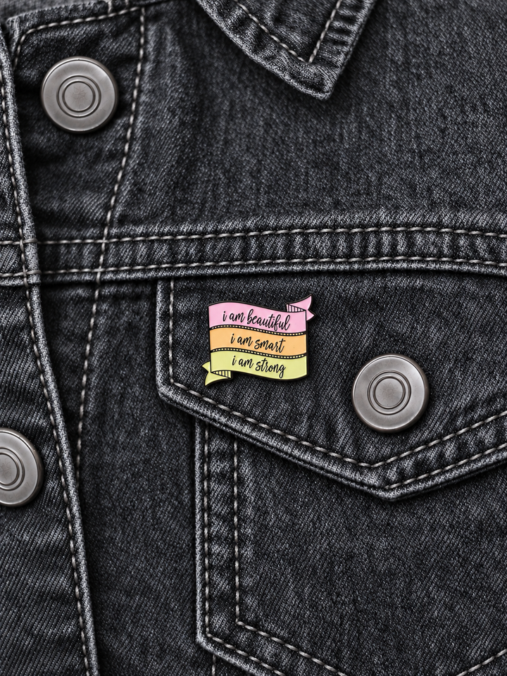 Beautiful Smart Strong Affirmation Pin displayed on a charcoal denim jacket beside a metal button
