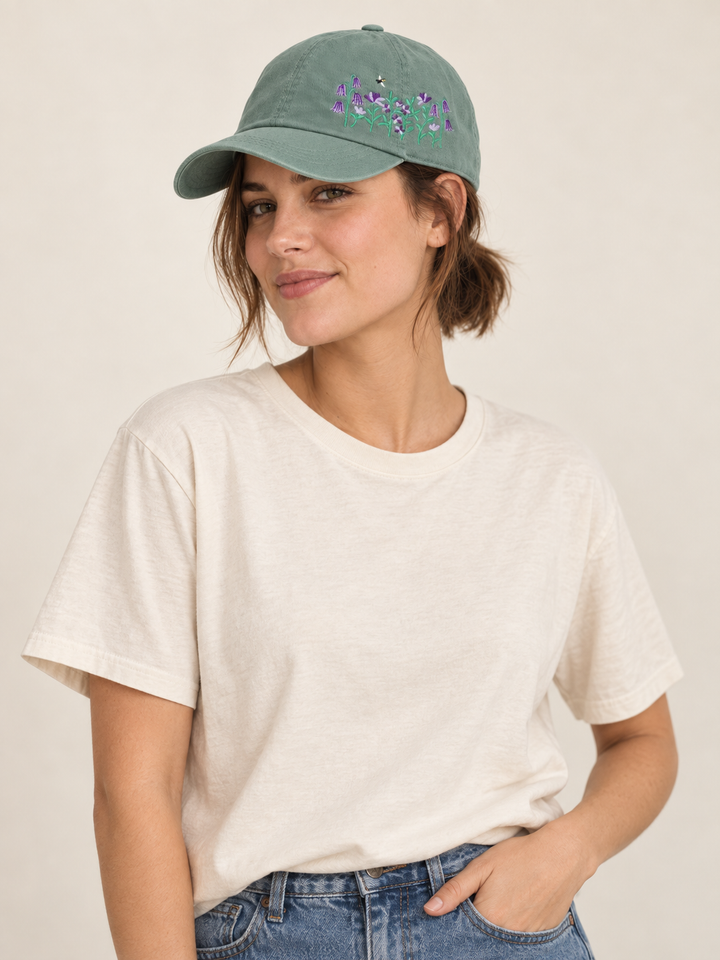 Model wearing a sage baseball cap with purple flower and bee embroidery