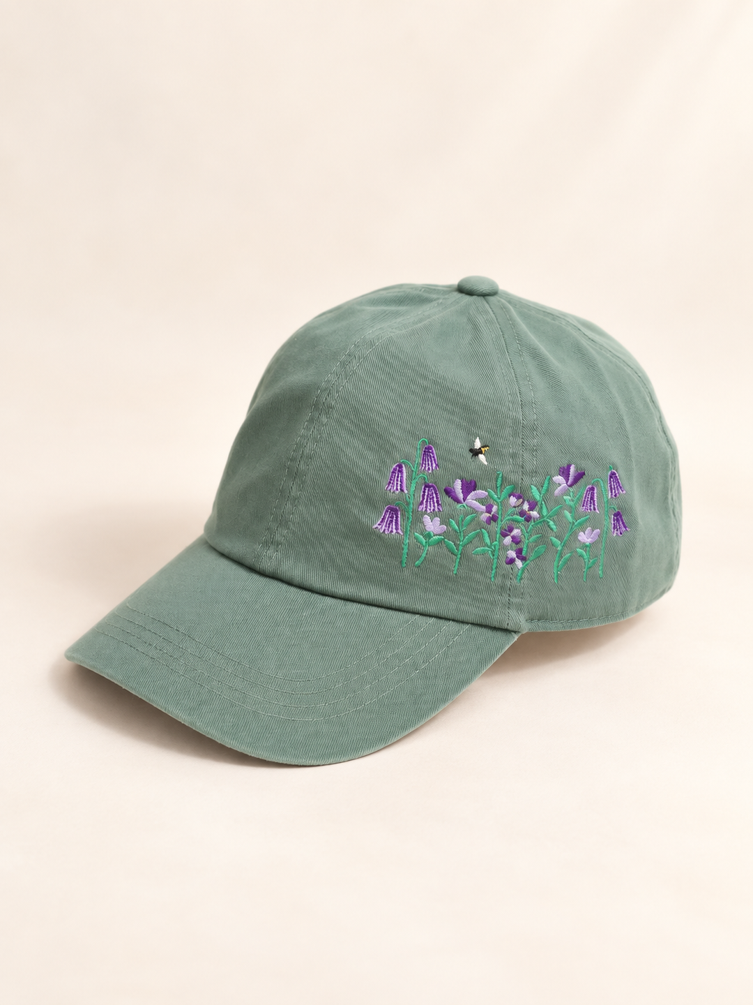 Three-quarter view of sage baseball cap with purple flowers and a bee