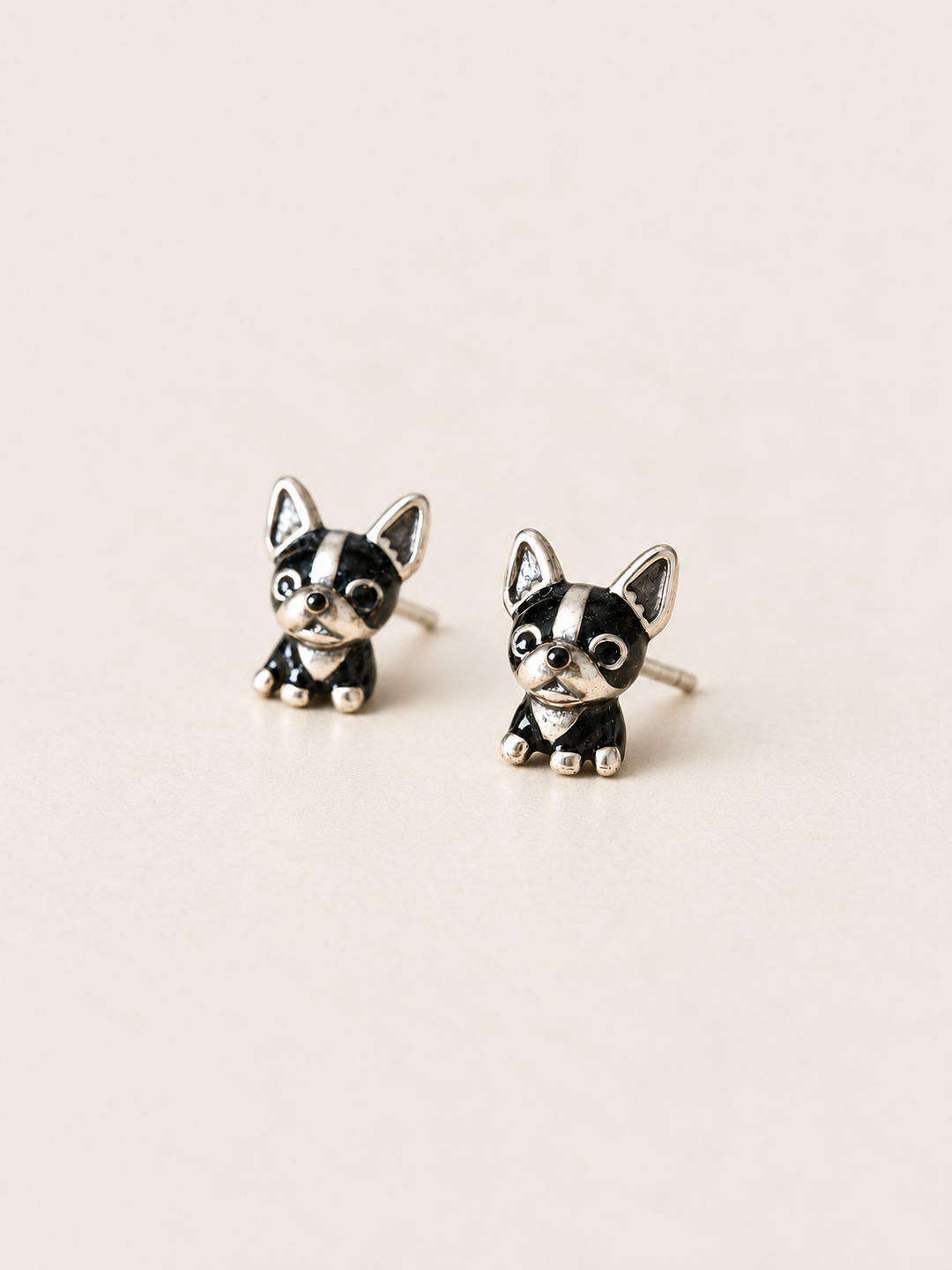 Black Dog Stud Earrings shown angled on a warm neutral background