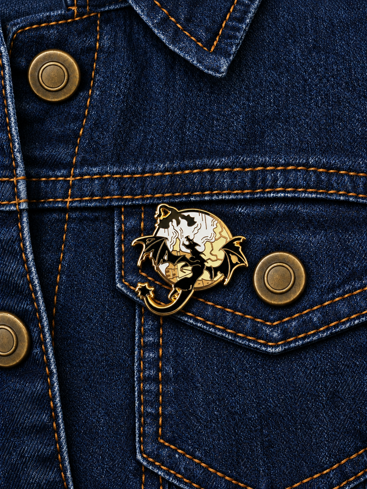 Black Dragon Reading Book Pin displayed on a dark indigo denim jacket beside a metal button