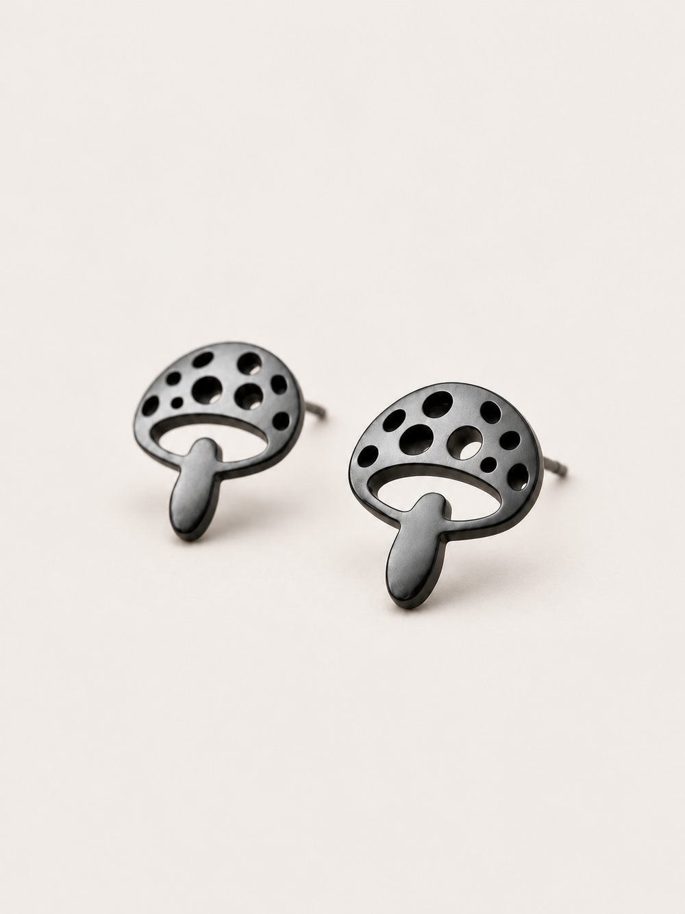 Black Mushroom Stud Earrings shown angled on a warm neutral background