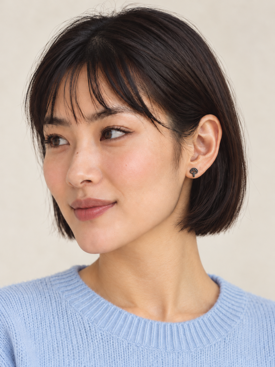 Black Mushroom Stud Earrings worn on the viewer-right ear