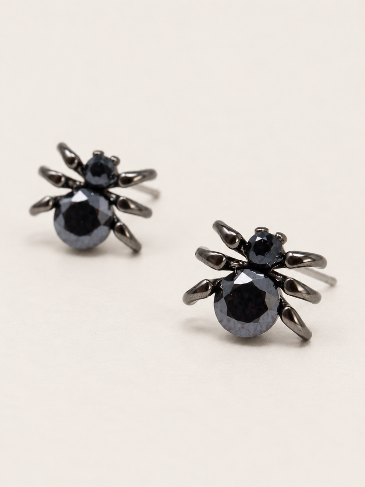 Black Spider Stud Earrings shown angled on a warm neutral background