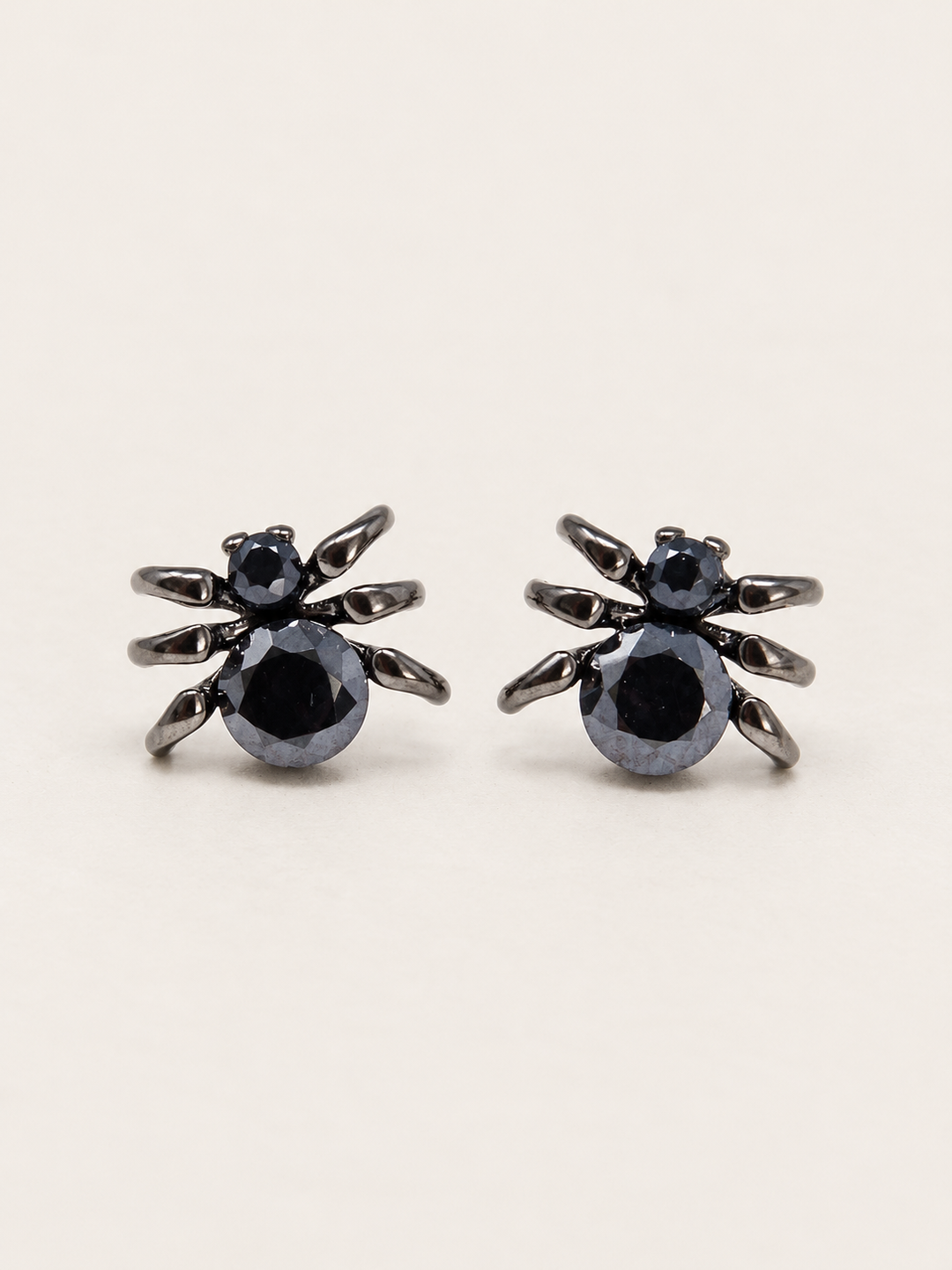 Black Spider Stud Earrings shown on a warm neutral background