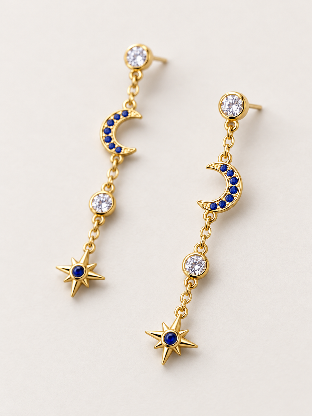 Blue Moon and Star Drop Earrings shown angled on a warm neutral background