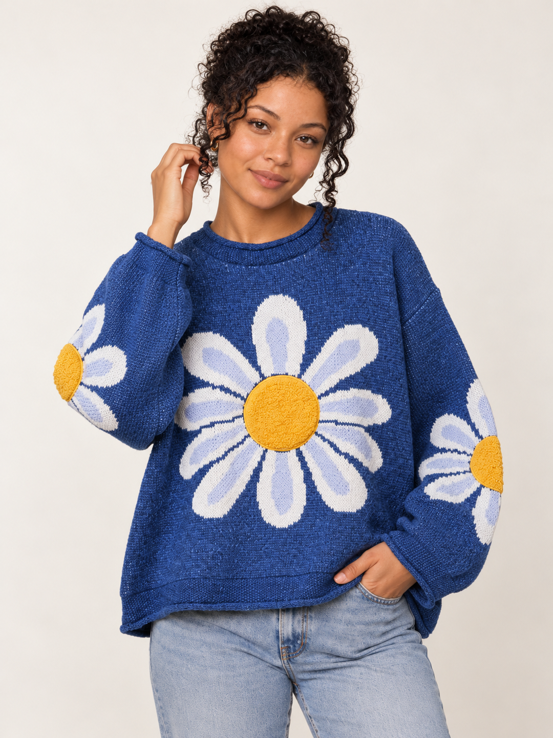 Front view of oversized blue daisy knit sweater with textured yellow flower centers