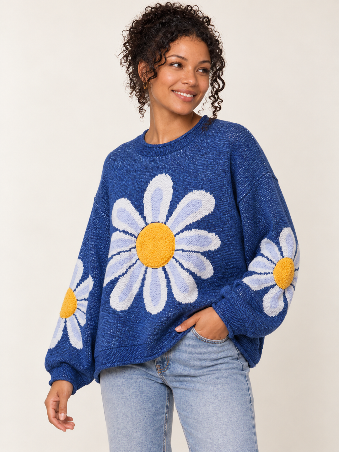 Angled view of blue oversized daisy sweater with dropped shoulders and long sleeves