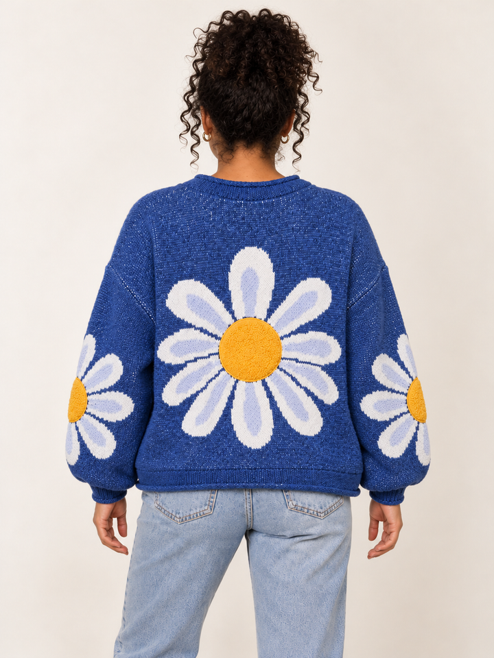 Back view of blue daisy knit sweater with large white and lavender flower