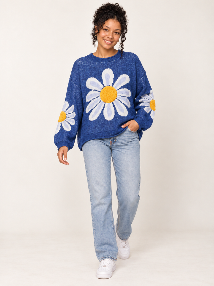 Full-body view of model wearing oversized blue daisy sweater with light-wash jeans