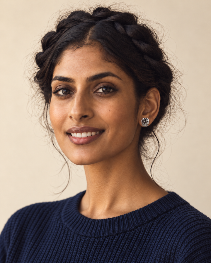 Silver Brain Stud Earrings worn on the viewer-right ear by a smiling model in a dark blue sweater