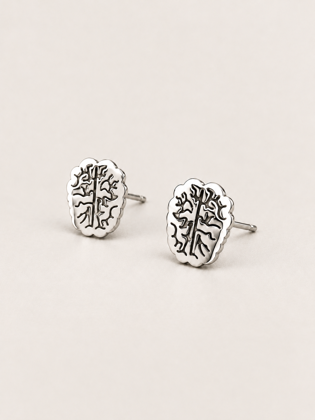 Silver Brain Stud Earrings shown angled on a warm neutral background