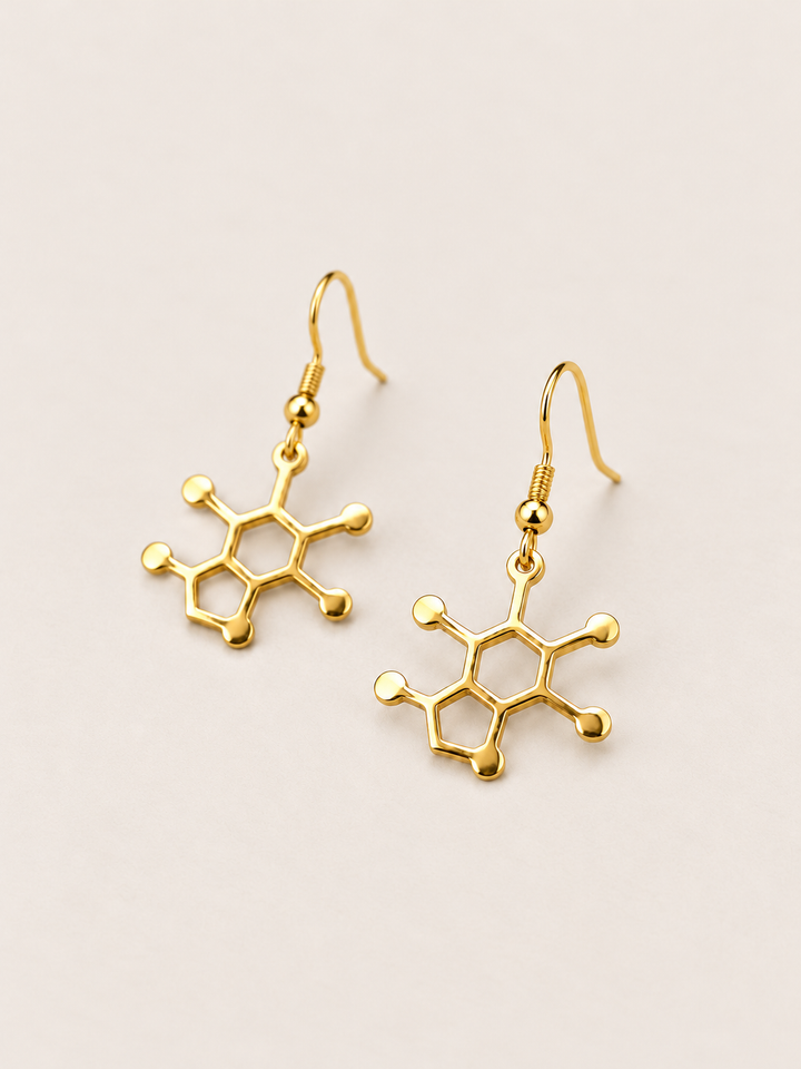 Gold Caffeine Molecule Earrings shown angled on a warm neutral background