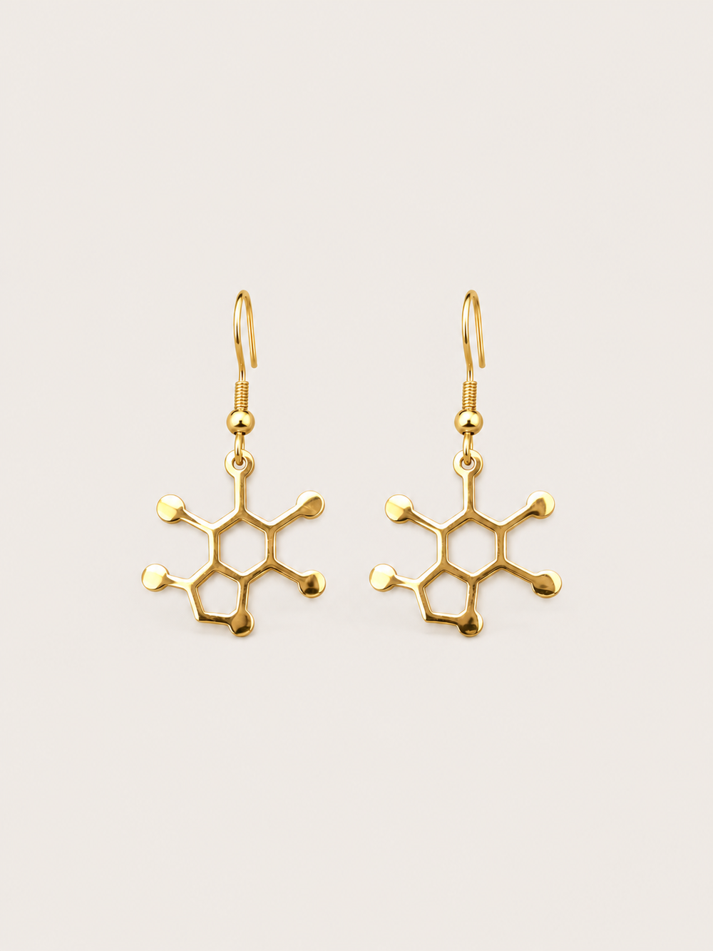 Gold Caffeine Molecule Earrings shown on a warm neutral background