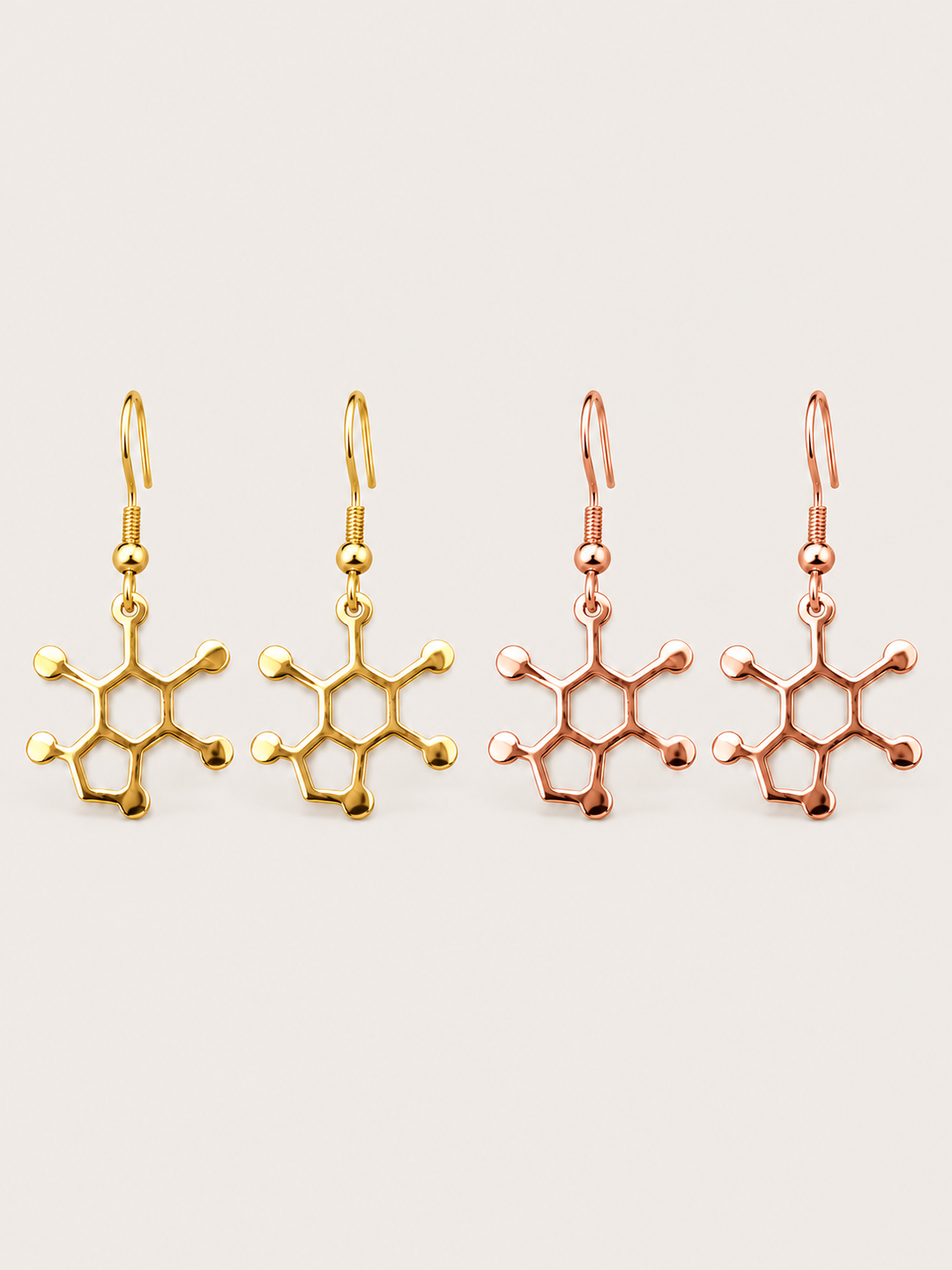 Caffeine Molecule Earrings in Gold and Rose Gold on a warm neutral background