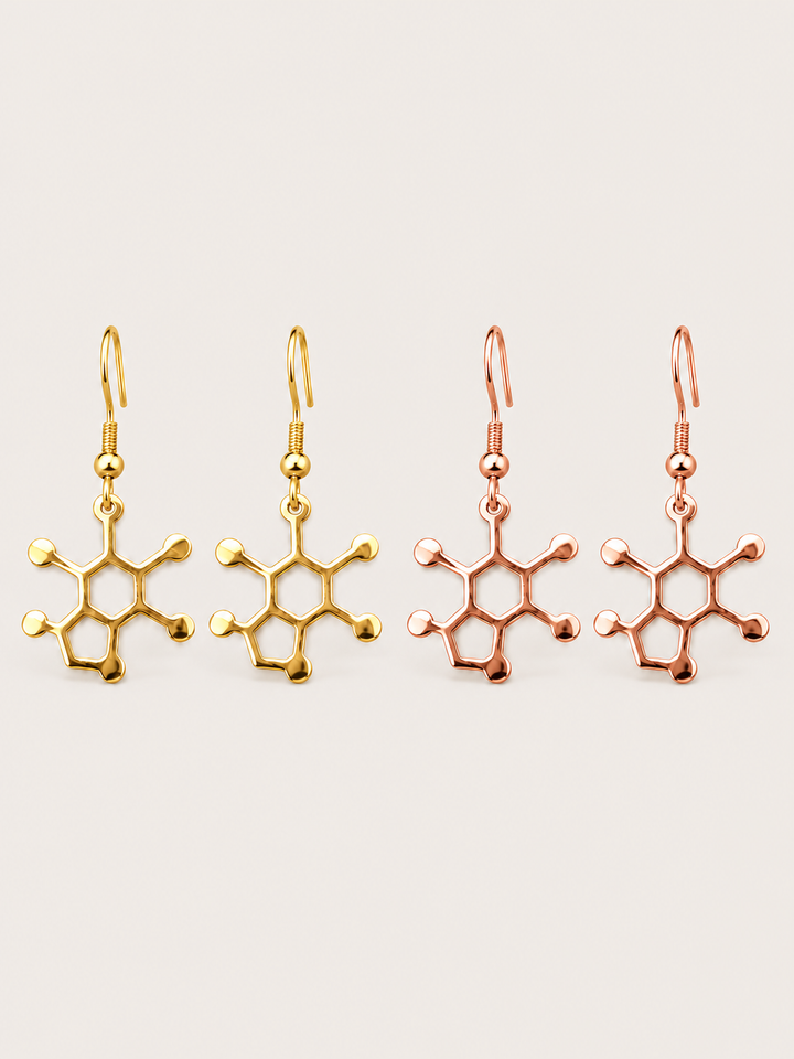 Caffeine Molecule Earrings in Gold and Rose Gold on a warm neutral background