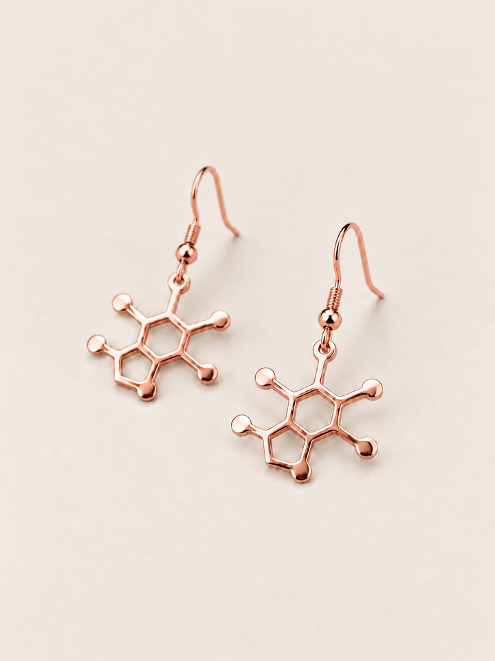 Rose Gold Caffeine Molecule Earrings shown angled on a warm neutral background