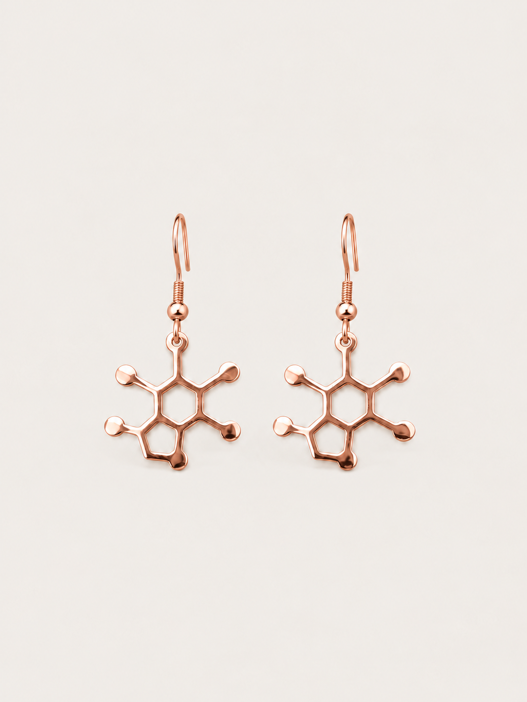 Rose Gold Caffeine Molecule Earrings shown on a warm neutral background