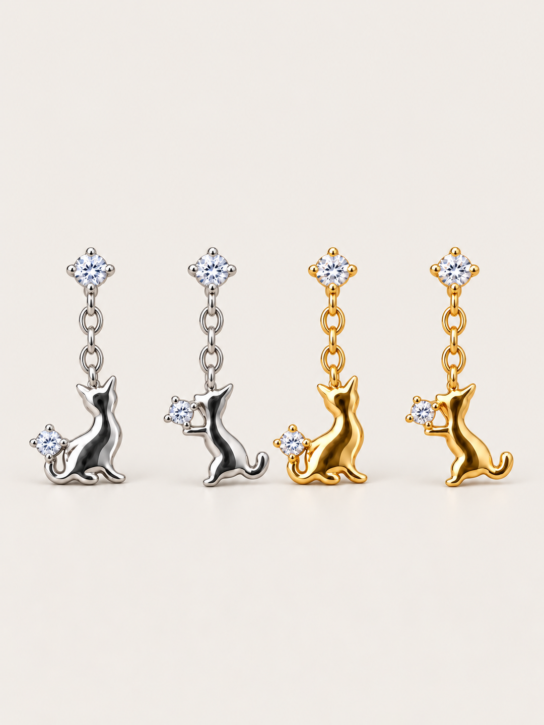 Cat Crystal Drop Earrings in silver and gold shown on a warm neutral background