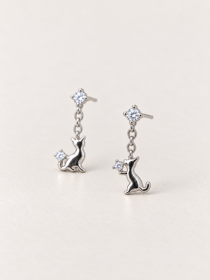 Silver Cat Crystal Drop Earrings shown angled on a warm neutral background