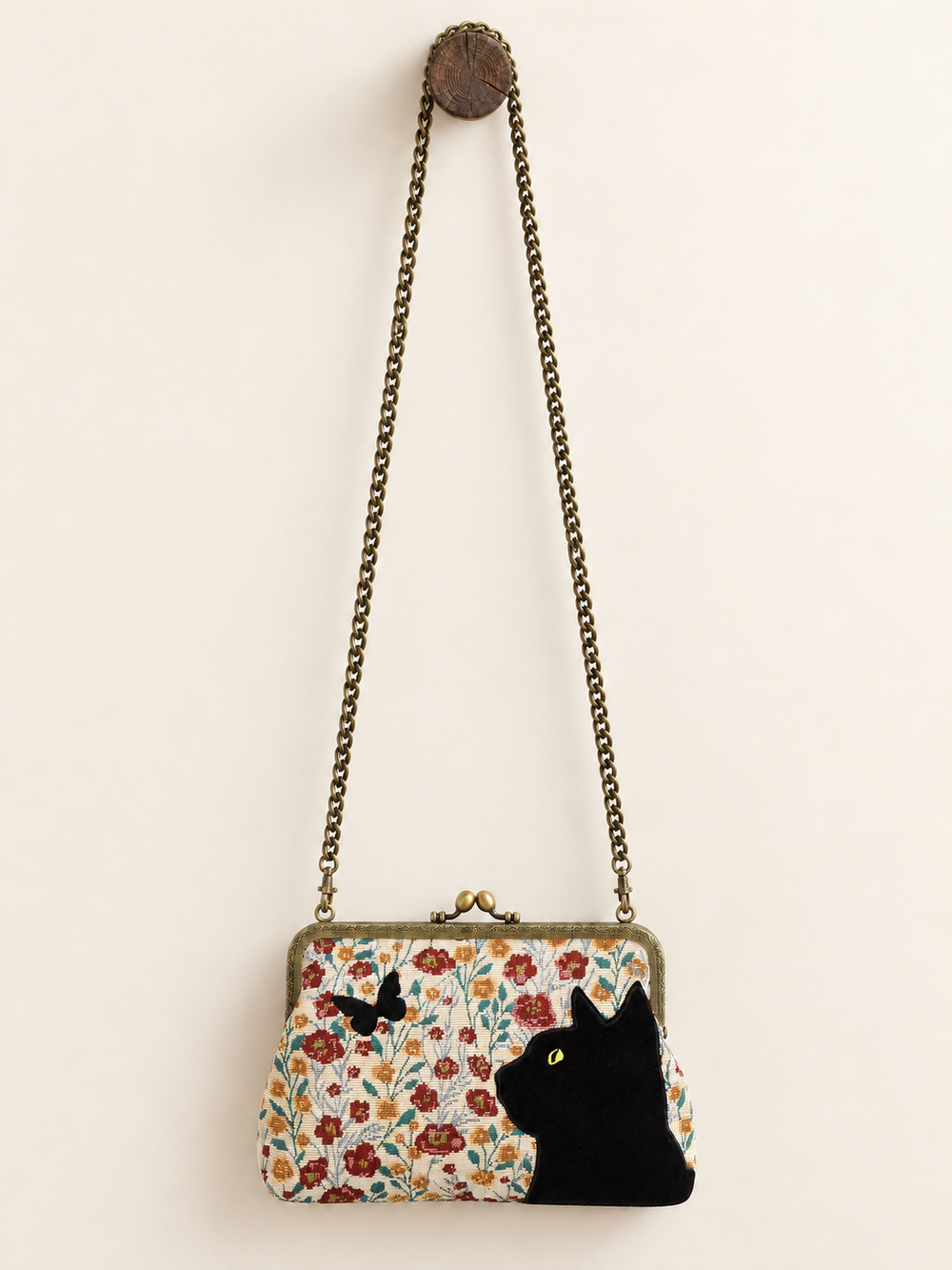 Cat Kisslock Bag with long chain visibly looped over wooden post