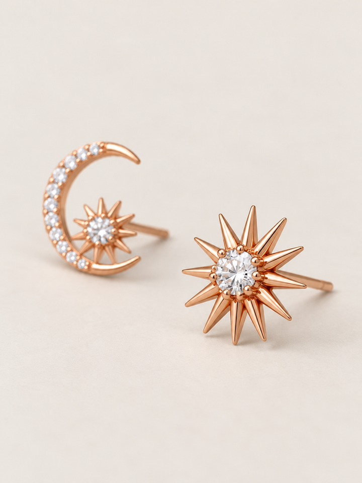Rose gold Celestial Moon and Starburst Earrings shown angled on a warm neutral background