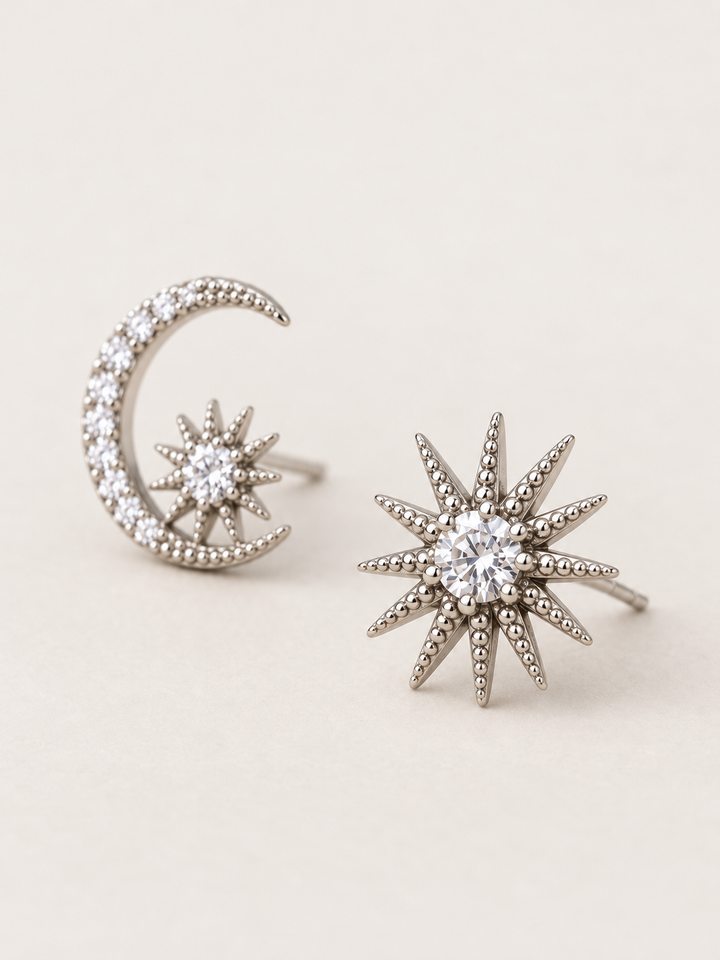 Silver Celestial Moon and Starburst Earrings shown angled on a warm neutral background