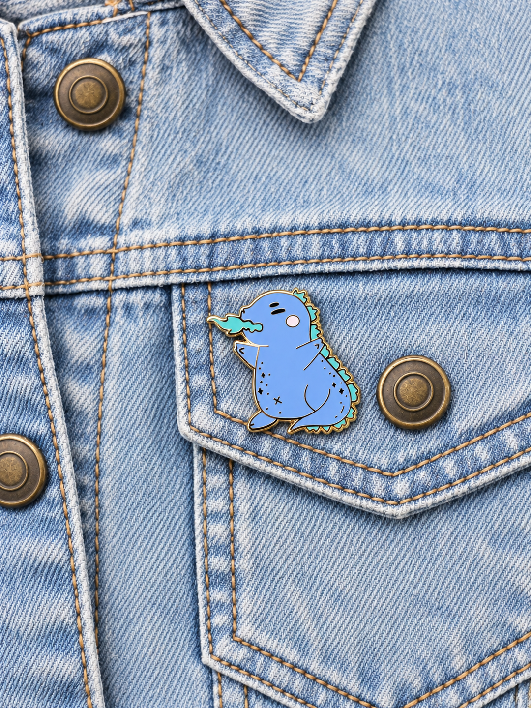 Chubby Blue Dragon Pin displayed on light-wash denim beside a metal button