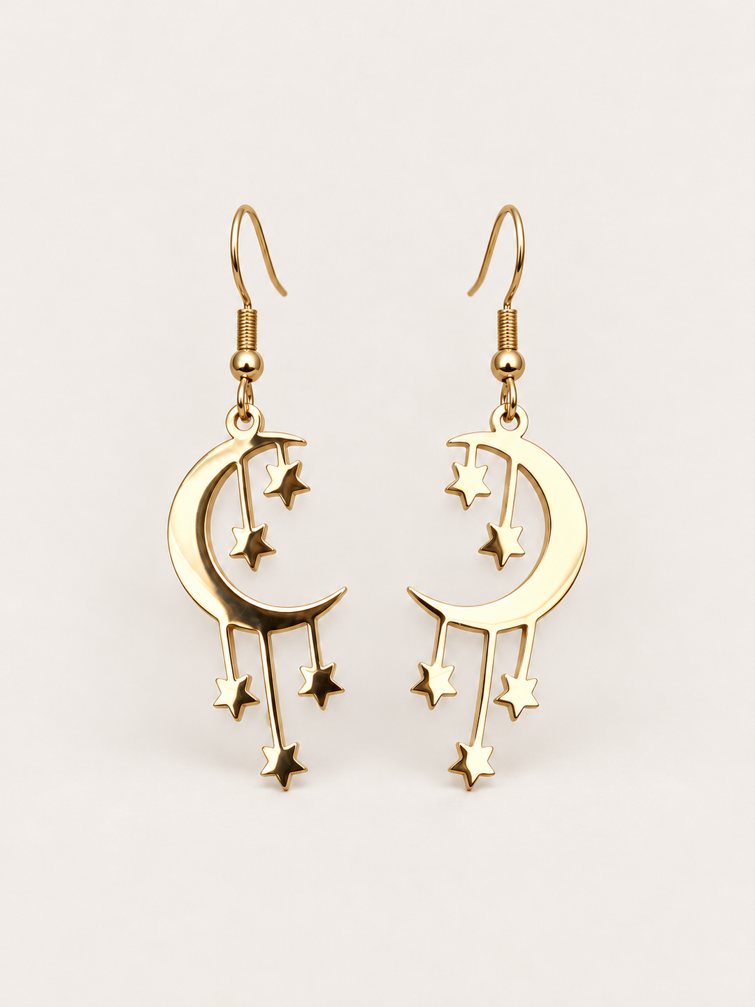 Gold Crescent Moon and Stars Drop Earrings on a warm neutral background