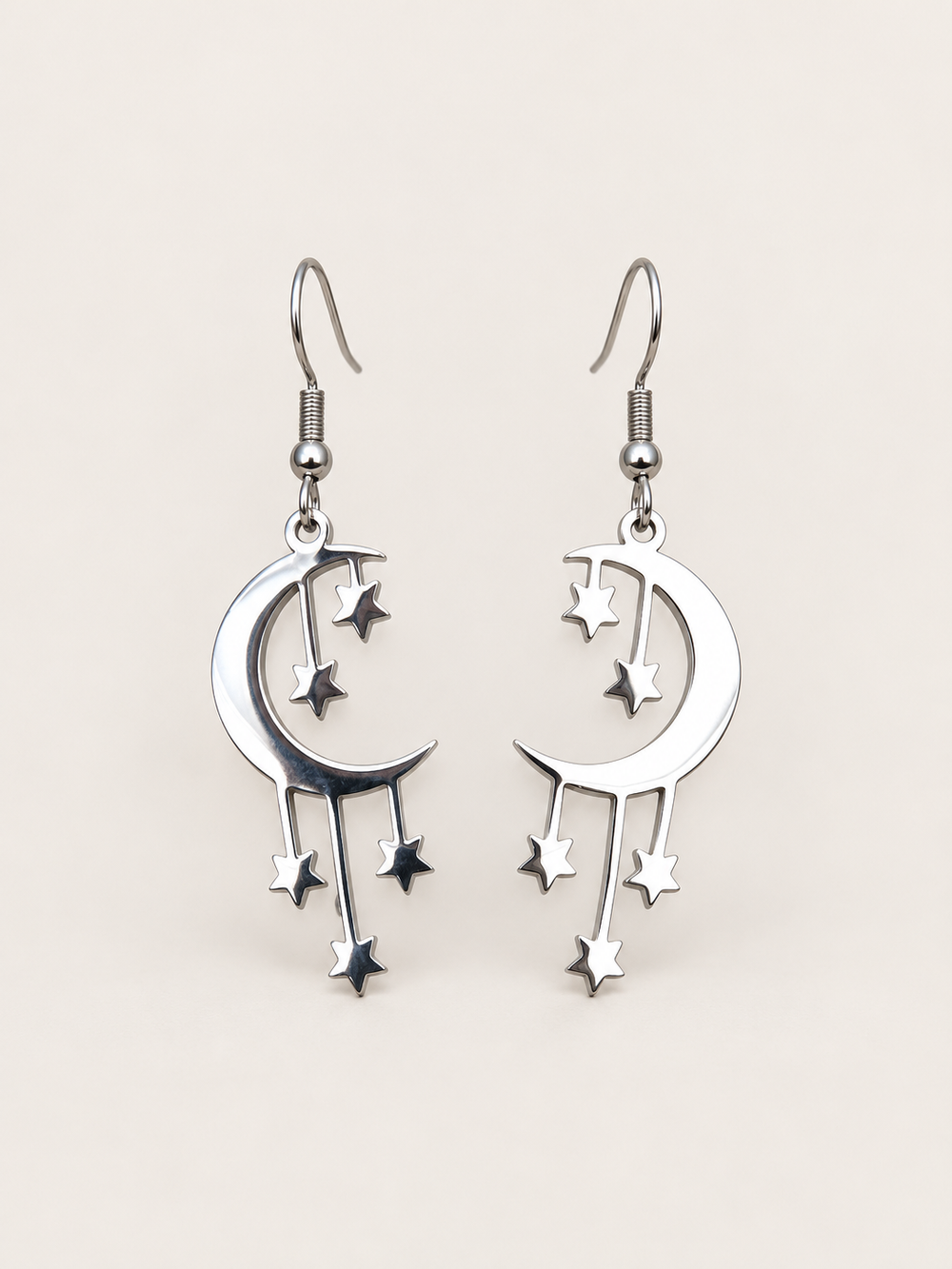 Silver Crescent Moon and Stars Drop Earrings on a warm neutral background