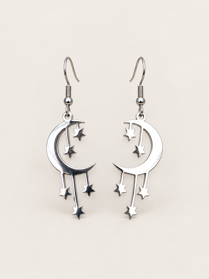 Silver Crescent Moon and Stars Drop Earrings on a warm neutral background