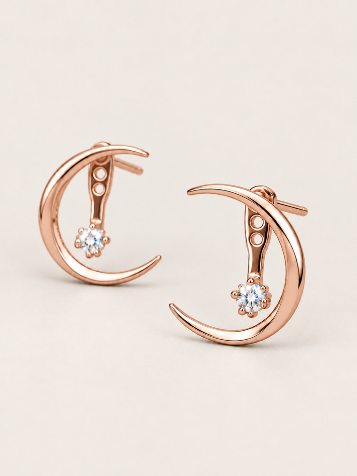 Crescent Moon Ear Jacket Earrings in Rose Gold shown angled on a warm neutral background