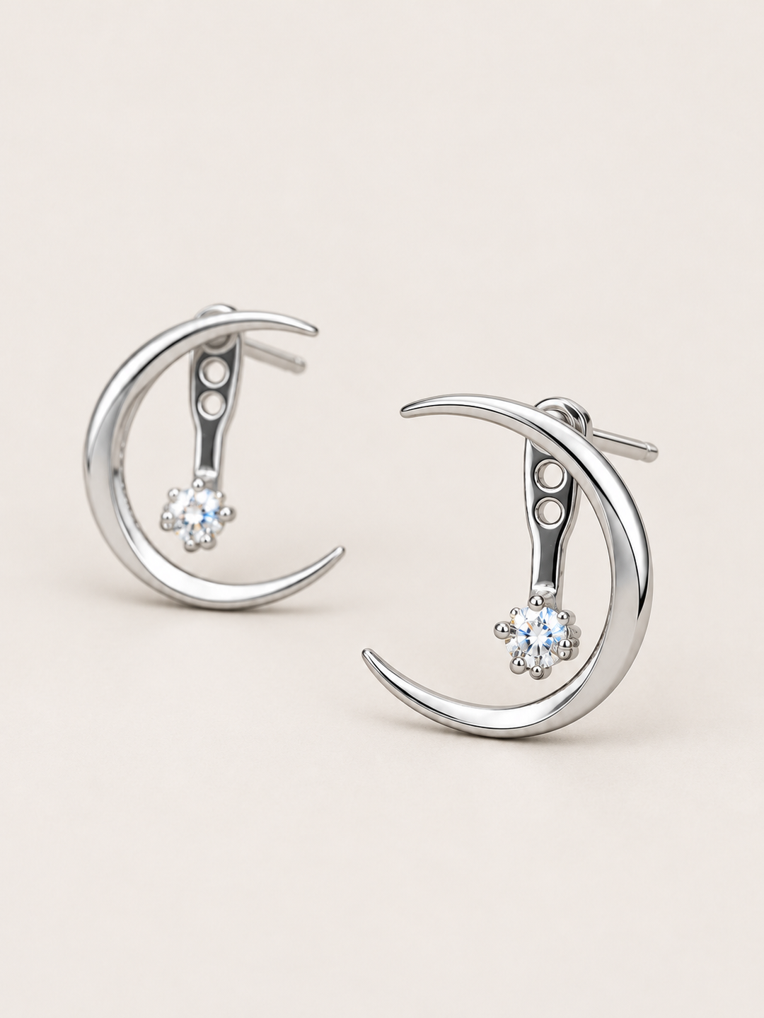 Crescent Moon Ear Jacket Earrings in Silver shown angled on a warm neutral background
